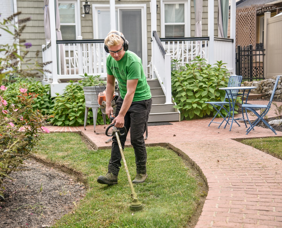 A landscaper edging a lawn beside a brick garden path